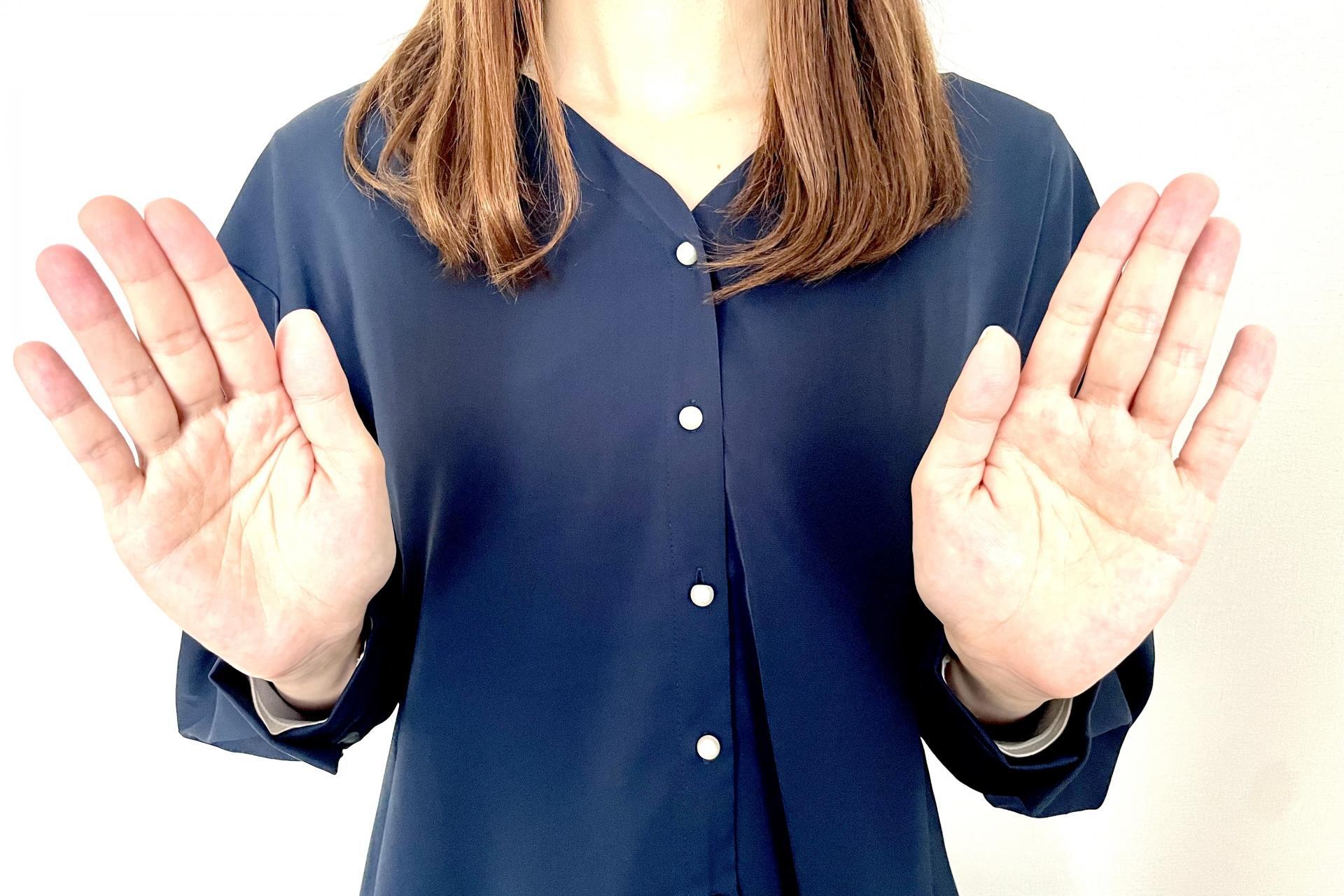 両手で拒否のポーズをとる女性