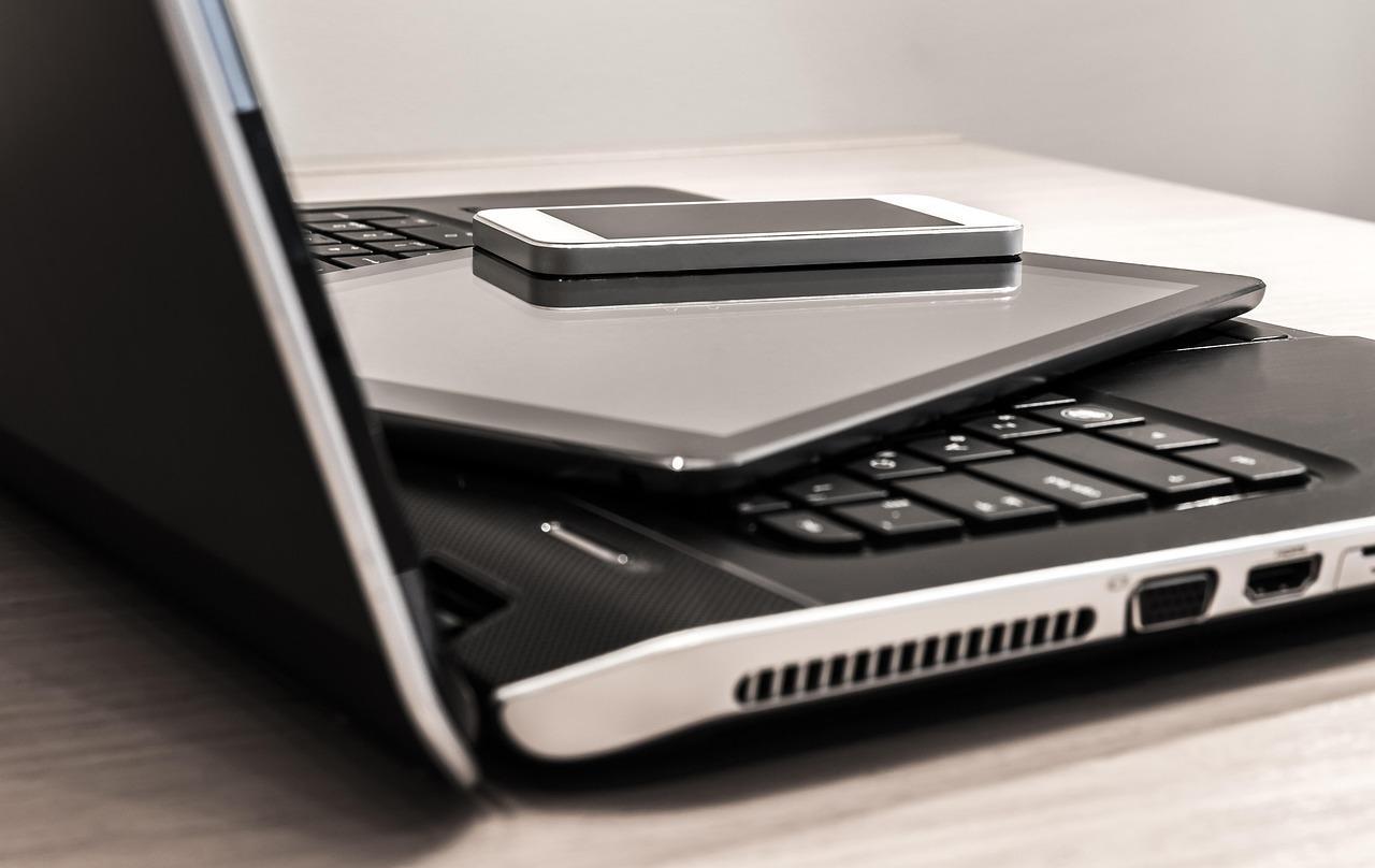 重ねられたノートPCやタブレット、スマートフォン